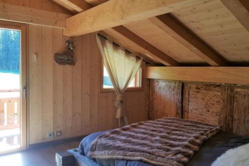 a bed in a room with a wooden ceiling at Le Chalet de Bequi in Bellefontaine