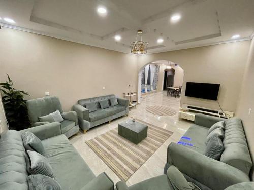Il comprend un salon avec des canapés et une télévision à écran plat. dans l'établissement استراحة شادن, à Yanbu