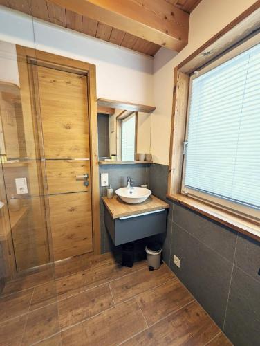 a bathroom with a sink and a shower and a window at Das Postfeld Appartement in Neukirchen am Großvenediger