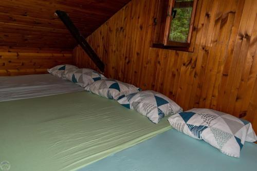 Bett mit vier Kissen in einem Holzzimmer in der Unterkunft Home Puščava in Kranj