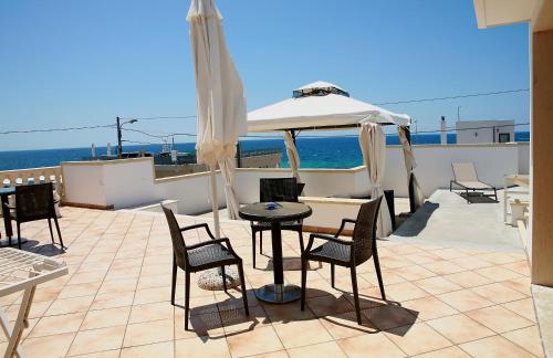 eine Terrasse mit einem Tisch, Stühlen und einem Sonnenschirm in der Unterkunft Hotel Villa Giovanna in Torre Suda