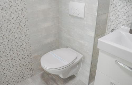 a white bathroom with a toilet and a sink at Beachfront apartment Plaza in Omiš