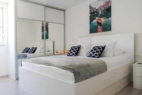 a white bedroom with a large white bed at Beachfront apartment Plaza in Omiš