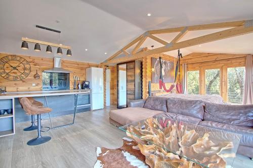 un salon avec un canapé et une cuisine dans l'établissement romantique cabane perchée avec spa vue panoramique Le Mas des faraches, à Solliès-Toucas