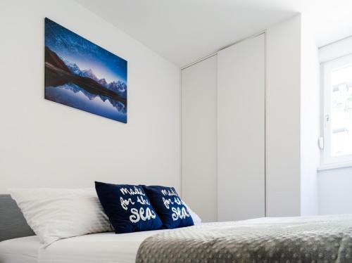 a bedroom with white walls and a bed with blue pillows at Beachfront apartment Plaza in Omiš