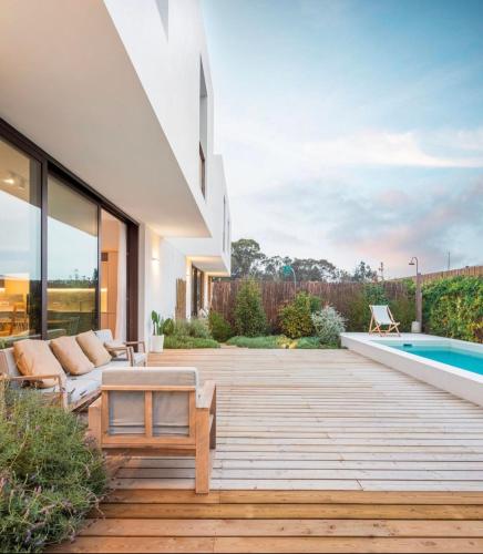 a backyard with a wooden deck and a swimming pool at Comporta.threeHouse in Brejos, Portugal in Comporta