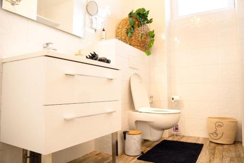 La salle de bains blanche est pourvue de toilettes et d'un lavabo. dans l'établissement La Menorah, au Creusot