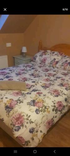 a bed with a floral comforter on top of it at Atlantic lodge in Ahnagh Cross