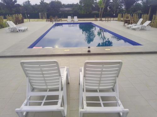 Allada的住宿－CENTRE NOURRI' SAINE，两把白色椅子坐在游泳池旁