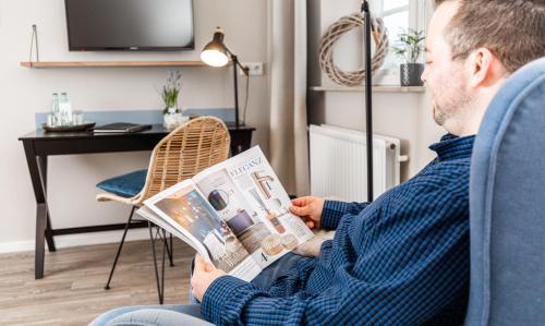 un hombre sentado en una silla leyendo una revista en Hotel & Restaurant Utspann Schafflund en Schafflund