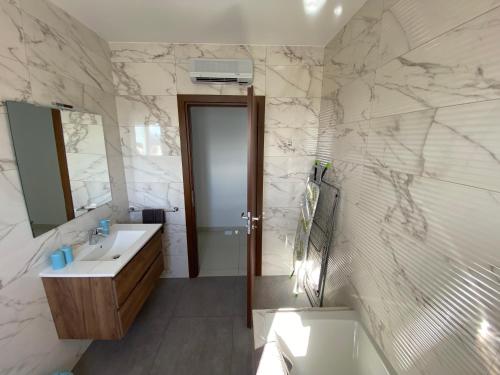 La salle de bains est pourvue d'un lavabo et d'un miroir. dans l'établissement Sunshine Apartments Mellieha - modern two bedroom penthouse with terrace, à Mellieħa