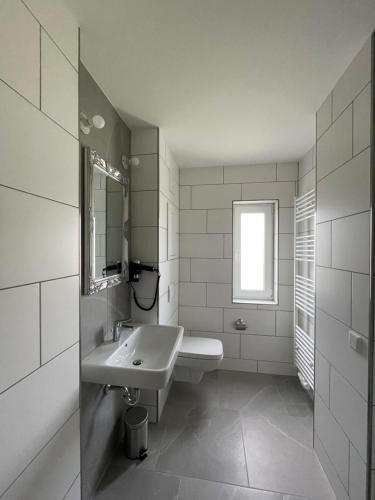 a white bathroom with a sink and a mirror at Haus 15 Apartments in Bielefeld