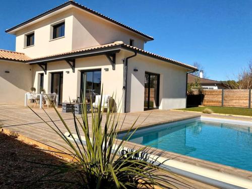 une maison avec une piscine devant dans l'établissement Villa entre Océan et Bassin, piscine chauffée, à Lège-Cap-Ferret