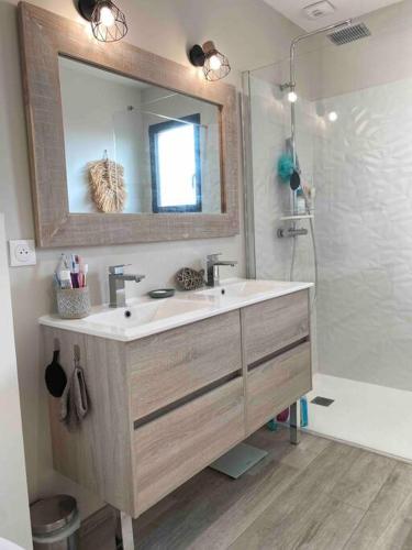 une salle de bain avec un lavabo, un miroir et une douche dans l'établissement Villa entre Océan et Bassin, piscine chauffée, à Lège-Cap-Ferret