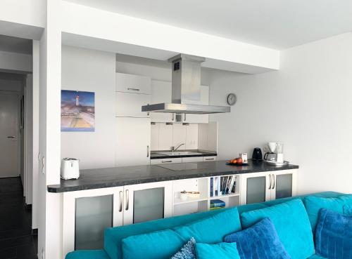 uma sala de estar com um sofá azul em frente a uma cozinha em Haus zur Mole - Morgenstern em Grossenbrode