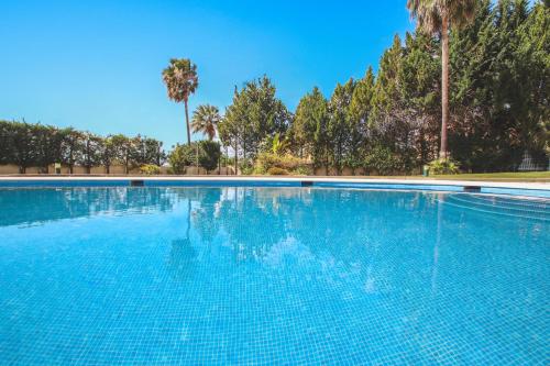a large blue swimming pool with palm trees in the background at Apartment Rhodes by Algarve Vacation in Albufeira
