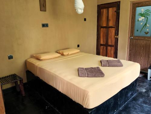 a bed in a room with two towels on it at Milk House Cottage in Udawalawe