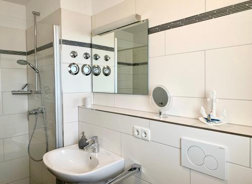 a white bathroom with a sink and a mirror at Haus zur Mole - Morgenstern in Großenbrode