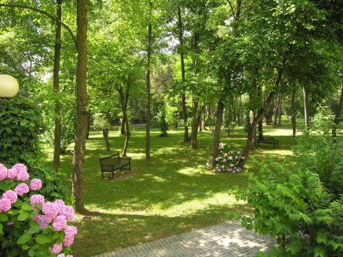two benches in a park with pink flowers and trees at Apartment Pine Wood in Bibione