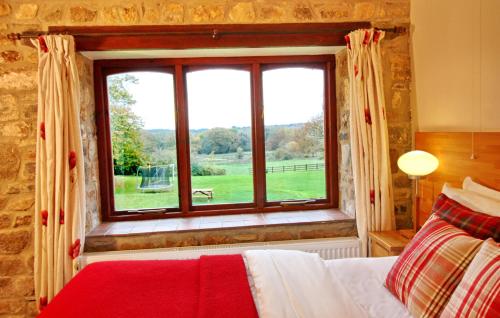 um quarto com uma cama e uma grande janela em David's Organic Farm Wales em Llanfallteg