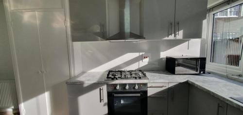 een witte keuken met een fornuis en een magnetron bij LONDON EXPERIENCE in Eltham