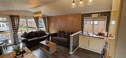 uma sala de estar com um sofá e uma cozinha em Tranquil Lodge hot tub and free golf em Swarland