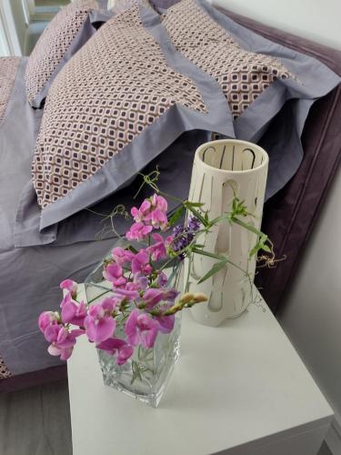 two vases and flowers on a table next to a bed at Le Chêne Olivet in Olivet