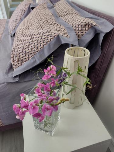 zwei Vasen und Blumen auf einem Tisch neben einem Bett in der Unterkunft Le Chêne Olivet in Olivet