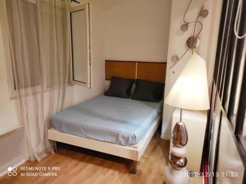 ein kleines Schlafzimmer mit einem Bett und einer Lampe in der Unterkunft Appartement idéal visite de Paris in Ivry-sur-Seine