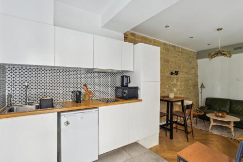 une cuisine avec des armoires blanches et un salon dans l'établissement Beau 3 pièces rue Poissonnière, à Paris