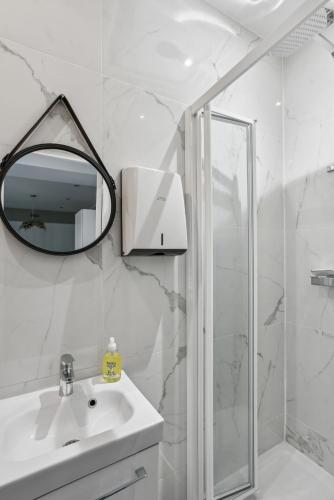 une salle de bain blanche avec un lavabo et un miroir dans l'établissement Beau 3 pièces rue Poissonnière, à Paris