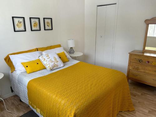 a bedroom with a bed with a yellow blanket at Chalet Mahigan Sipy in Saint-Paulin