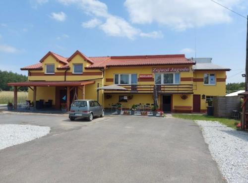 a car parked in front of a yellow house at Zajazd Jagoda Pokoje i Restauracja 