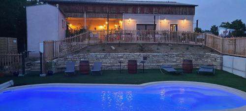 a swimming pool with chairs and a house in the background at L'Escale Occitane in Alzonne