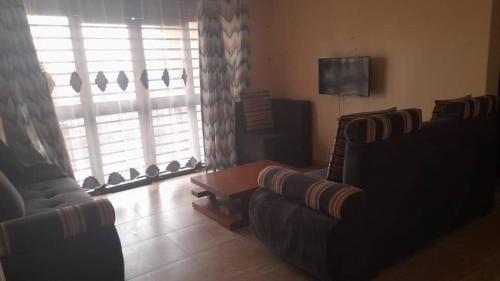 a living room with two couches and a tv at Nelly Apartments in Mbale