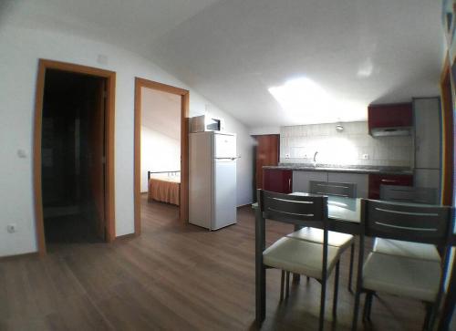 a kitchen with a table and chairs and a refrigerator at Gala T1+ in Figueira da Foz