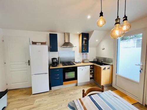 La cuisine est équipée de placards bleus et d'un réfrigérateur blanc. dans l'établissement Maison de la pinède, accès direct forêt et plage, à Notre-Dame-de-Monts
