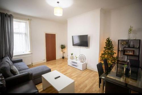 een woonkamer met een bank en een kerstboom bij Cozy Room @ Wallsend in Old Walker