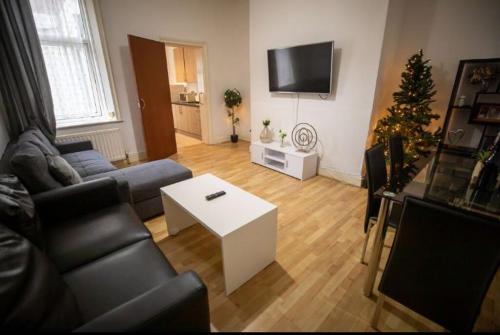 a living room with a couch and a christmas tree at Cozy Room @ Wallsend in Old Walker