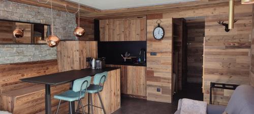 une cuisine avec des murs en bois et un comptoir avec des tabourets dans l'établissement Grands studios vue sur lac, à Tignes