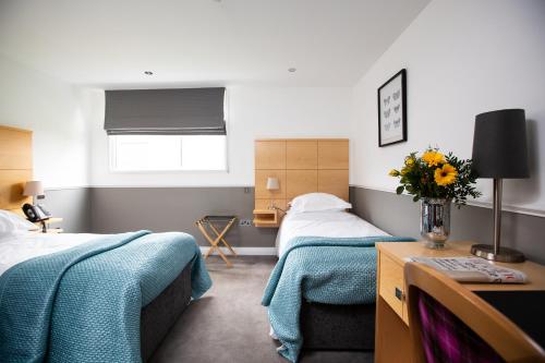 a bedroom with two beds and a vase of flowers at Accommodation at Salomons Estate in Royal Tunbridge Wells
