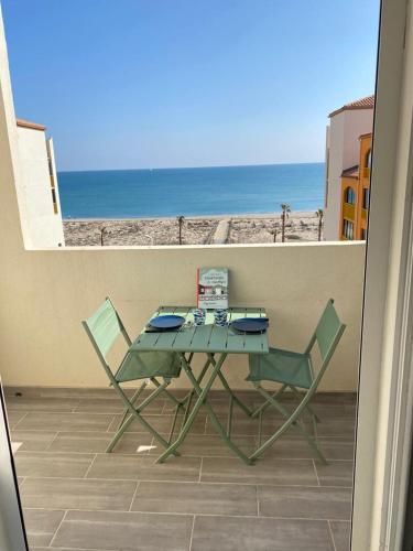 d'une table et de deux chaises sur un balcon donnant sur la plage. dans l'établissement Paradis bleu vue mer, direct plage, au Barcarès