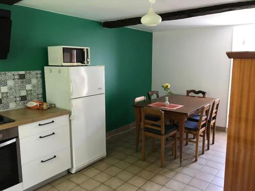 eine Küche mit einem Tisch und einem weißen Kühlschrank in der Unterkunft Gîte au coeur de la campagne normande in Ouville