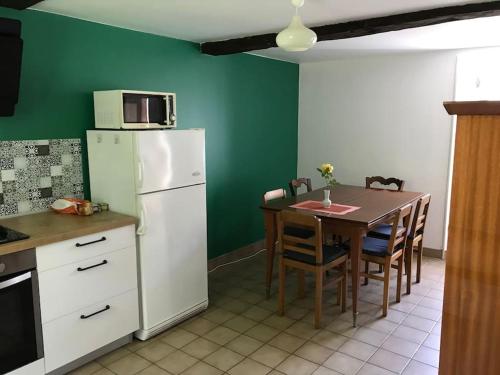 une cuisine avec une table et un réfrigérateur blanc dans l'établissement Gîte au coeur de la campagne normande, à Ouville