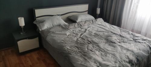a bed with a gray comforter and two pillows at Apartament în regim Hotelier in Cavnic