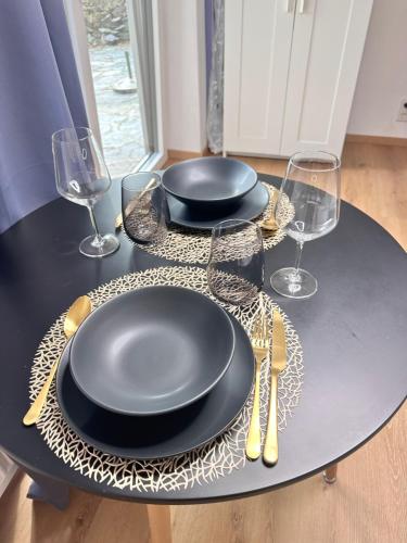 a table with two black plates and glasses on it at Grimming Lodge Tauplitz in Tauplitz