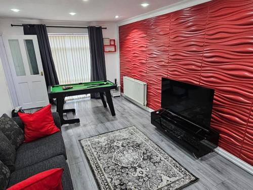 a living room with a red wall with a pool table at Airbnb Palace in Birmingham