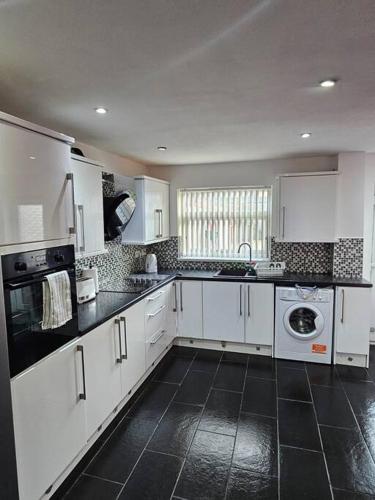 a kitchen with white cabinets and a black tile floor at Airbnb Palace in Birmingham