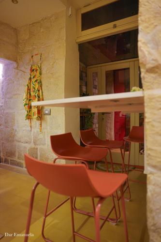 a group of red chairs and a bar in a restaurant at 150 years old Maltese Townhouse: Dar Emanuela in Cospicua
