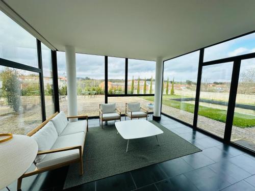a living room with a couch and chairs and windows at PÉ AZUL - Turismo em Espaço Rural - Parque Natural de Montesinho in Bragança